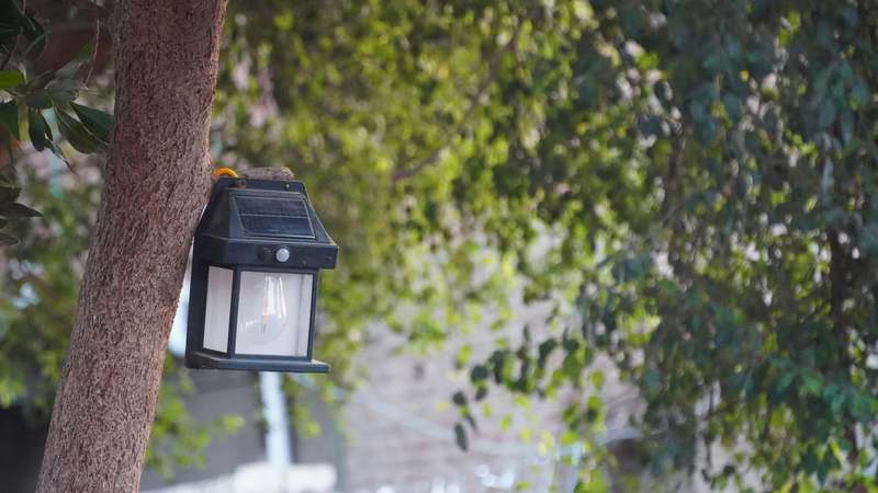 Close-up of a weatherproof LED security floodlight mounted under an eave, emitting focused white light on a dark driveway