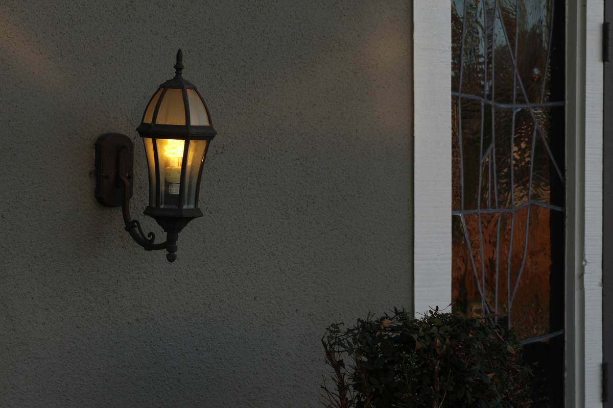 home security lighting tips showing properly angled motion-sensor floodlights covering driveway and front walkway, no glare on windows or neighboring property